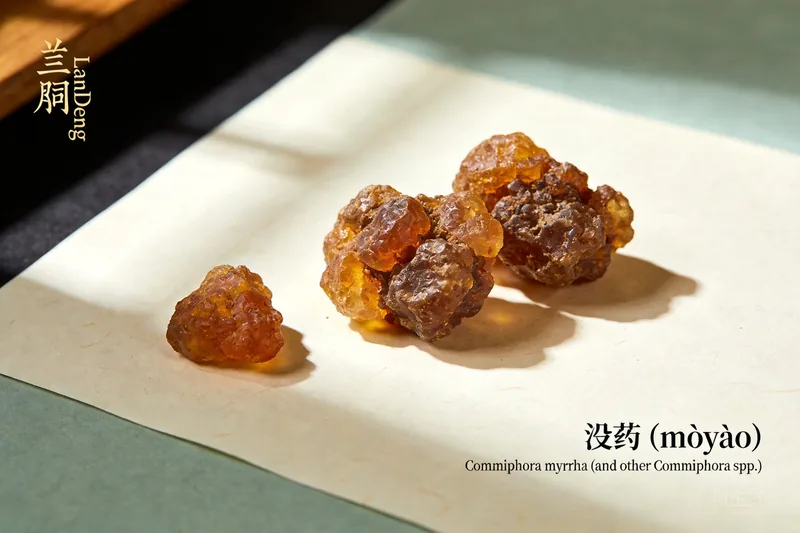 Dark reddish-brown myrrh resin tears on a stone dish.